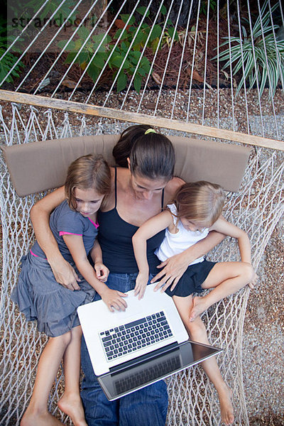 Mutter und Töchter auf Hängematte mit Laptop