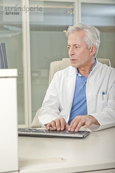 Arzt benutzt Computer am Schreibtisch