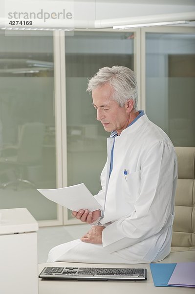 Arzt am Schreibtisch liest ein Dokument