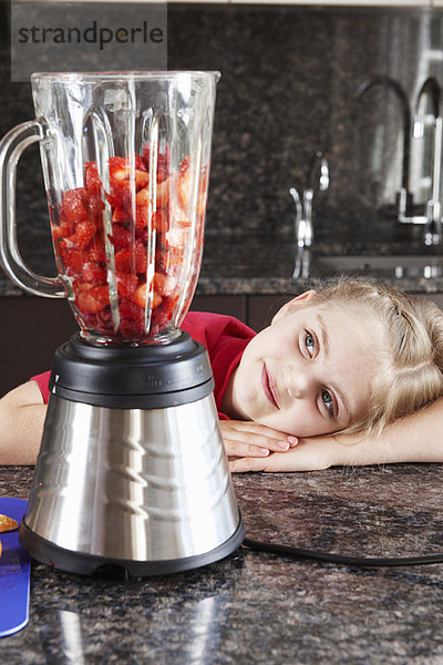 Mädchen schaut auf Obst im Mixer