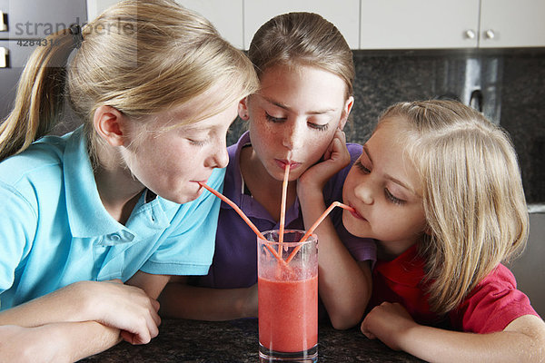 Mädchen trinken Fruchtsaft mit Strohhalmen