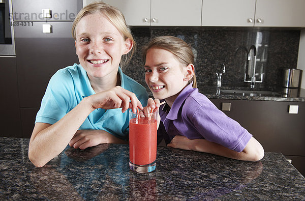 Mädchen trinken Fruchtsaft mit Strohhalmen