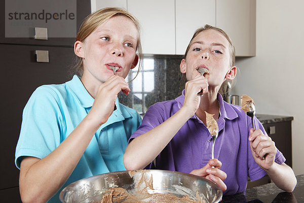 Mädchen essen Kuchenmischung in der Küche