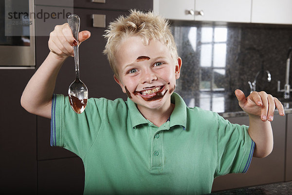 Junge in der Küche mit Kuchenmischung im Gesicht