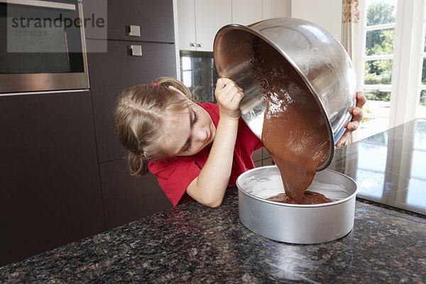 Mädchen gießen Kuchenmischung in die Kuchenform