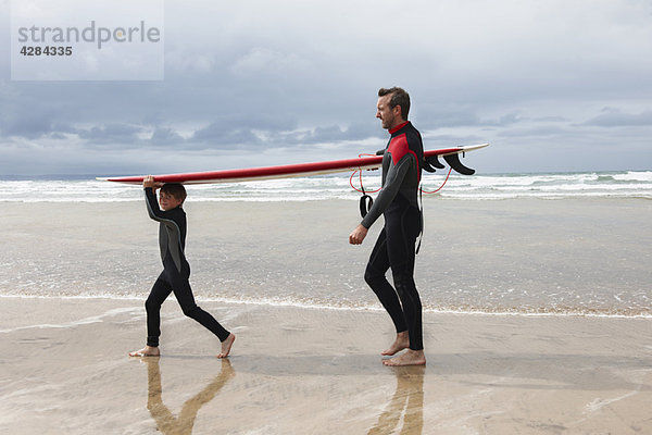 Vater und Sohn tragendes Surfbrett