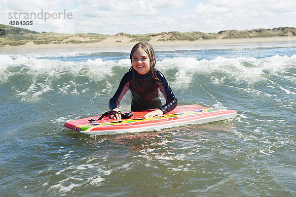 Junges Mädchen im Meer mit Surfbrett