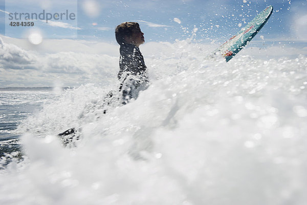 Kleiner Junge beim Surfen durch die Wellen