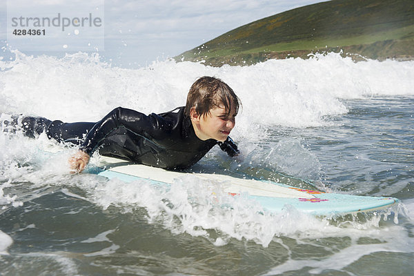 Junge surft auf einer Welle