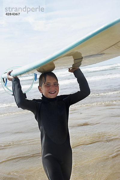 Kleiner Junge mit Surfbrett auf dem Kopf