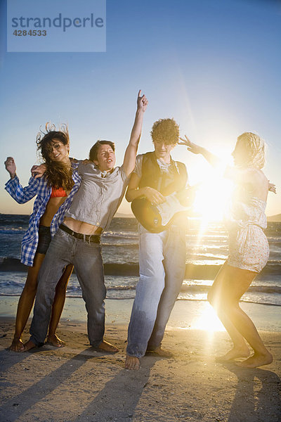 Junge Gruppe mit Gitarrentanz am Strand