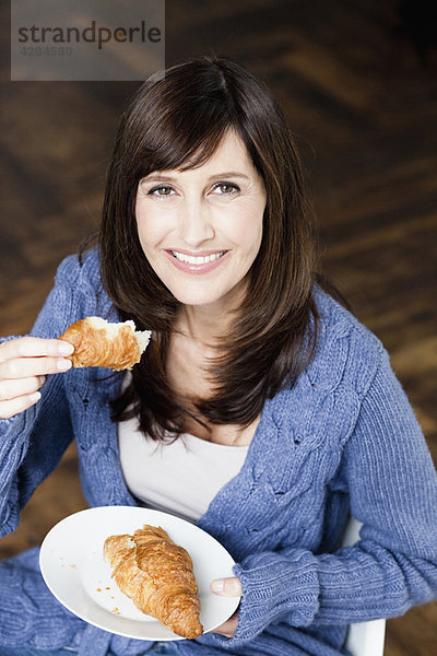 Frau isst Croissant