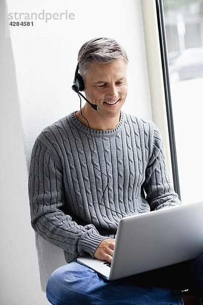 Mann mit Laptop-Telefonie