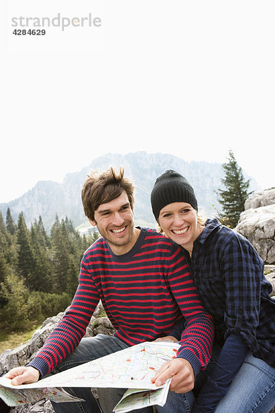 Paar mit Karte auf Felsen sitzend