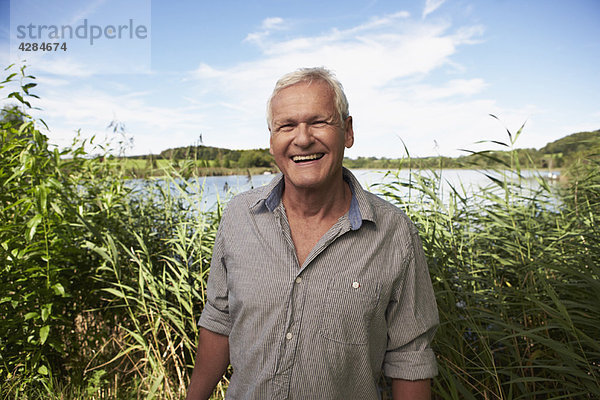 Älterer Mann steht vor dem See