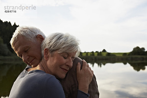 Seniorenpaar beim Umarmen vor dem See