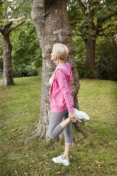 Reife Frau streckt Bein im Park