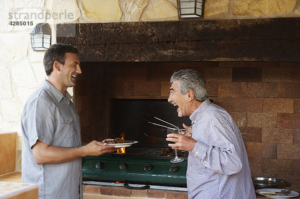 Zwei Männer  die beim Grillen zusammen lachen.