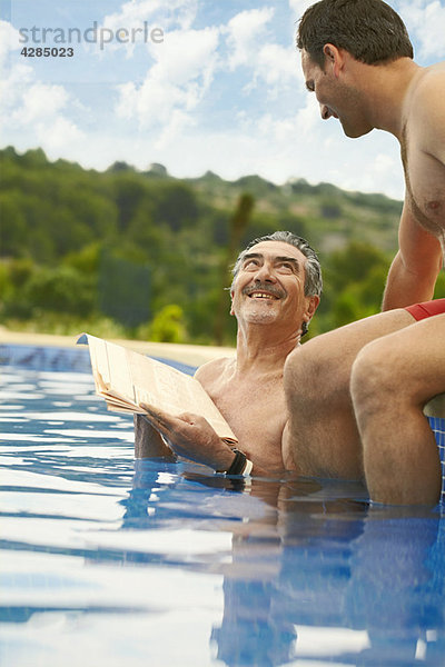 Älterer Mann beim Lesen von Nachrichten im Schwimmbad