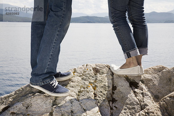 Mann und Frau auf dem Felsen am Meer stehend