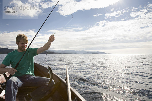 Mann beim Fischen auf einem Holzboot