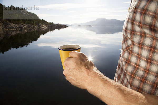 Mann beim Kaffee auf dem Seeweg und in den Bergen