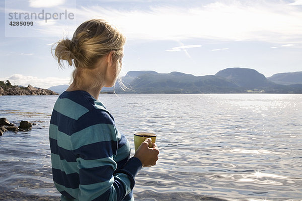 Frau mit Kaffee am Meer und in den Bergen