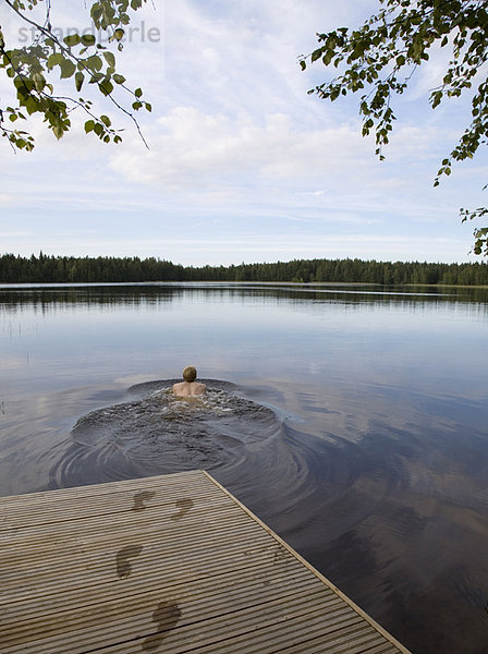 Mann schwimmt im stillen See