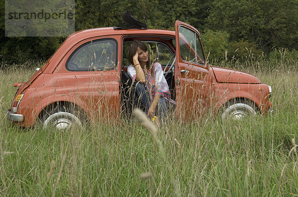 Entspanntes weibliches Sitzen im Auto im Feld