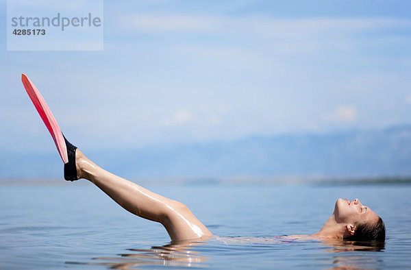 Frau schwimmt mit Flossen am Strand