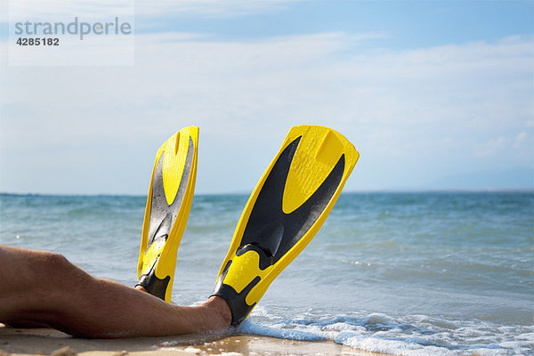 Mann mit Flossen am Strand