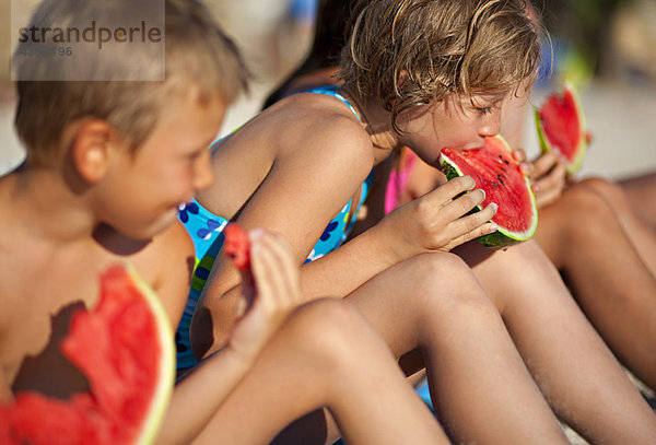 Kinder essen Wassermelone am Strand