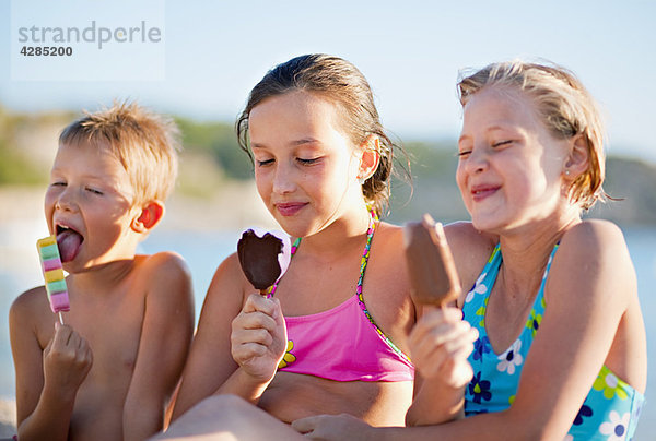 Kinder essen Eis am Strand