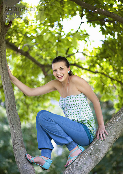 Junge Frau klettert Baum