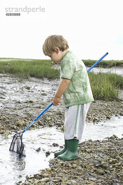 Kleiner Junge beim Fischen mit Netz