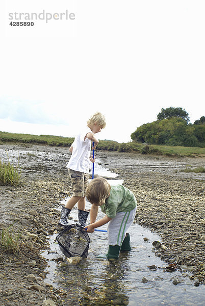 Zwei Jungen beim Fischen mit Netzen im Bach