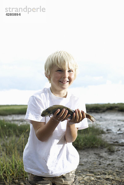 Junge hält Fische hoch