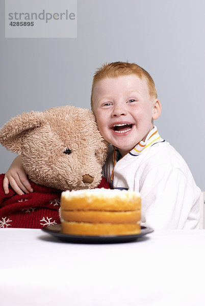 Junge mit Teddy und Kuchen