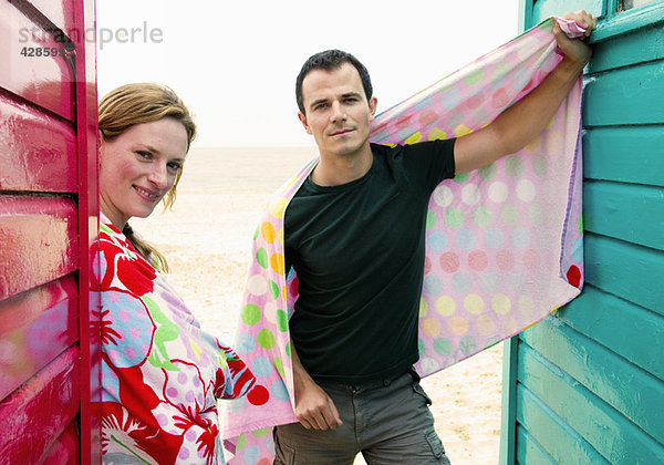 Paar mit Handtüchern entspannen bei Strandhütten