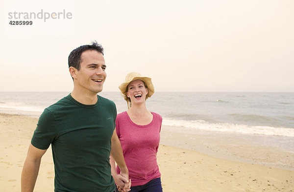 Ein glückliches Paar geht am Strand spazieren.