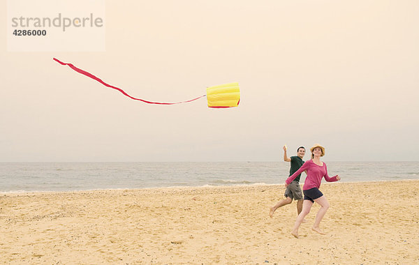 Glückliches Paar fliegen Drachen am Strand