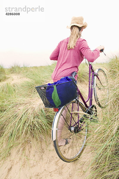 Frauen schieben Fahrrad über den Strand