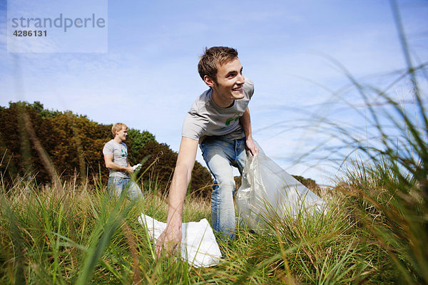 Junger Mann sammelt Müll in der Natur