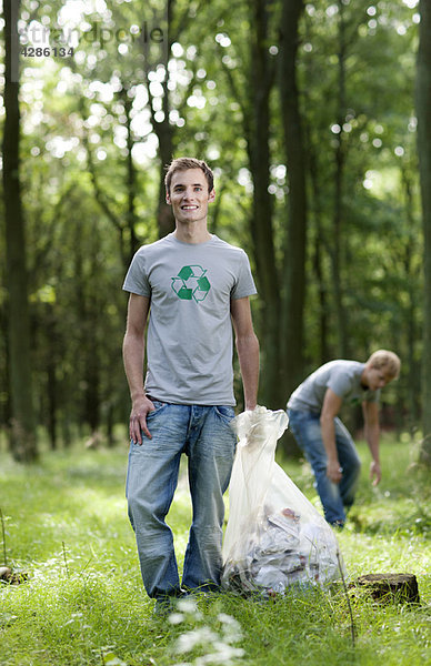 Junger Mann mit Müllsack in der Natur