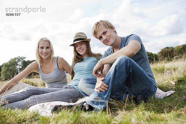 Drei Jugendliche im Gras sitzend