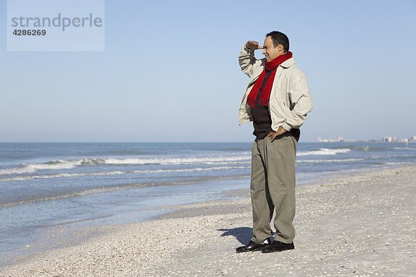 Mann am Strand stehend mit Blick auf die Aussicht