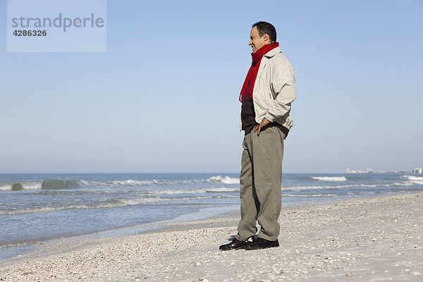 Mann am Strand stehend mit Blick auf die Aussicht