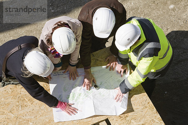 Architektengespräch mit dem Bauunternehmer auf der Baustelle zur Überprüfung der Entwürfe