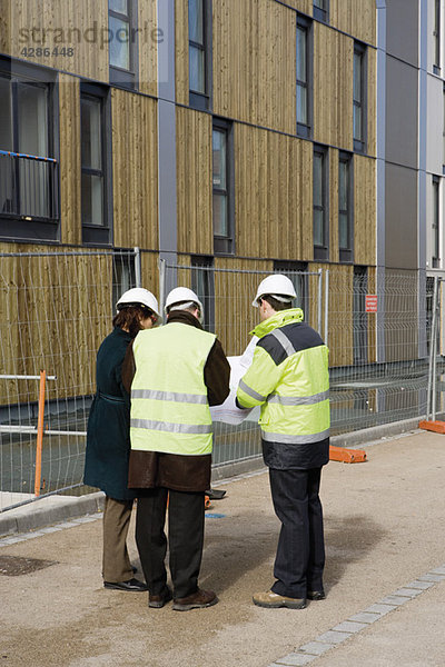 Bauunternehmer und Architekten im Gespräch auf der Baustelle