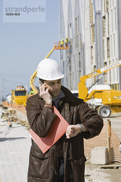Bauunternehmer mit Handy  Zeitkontrolle